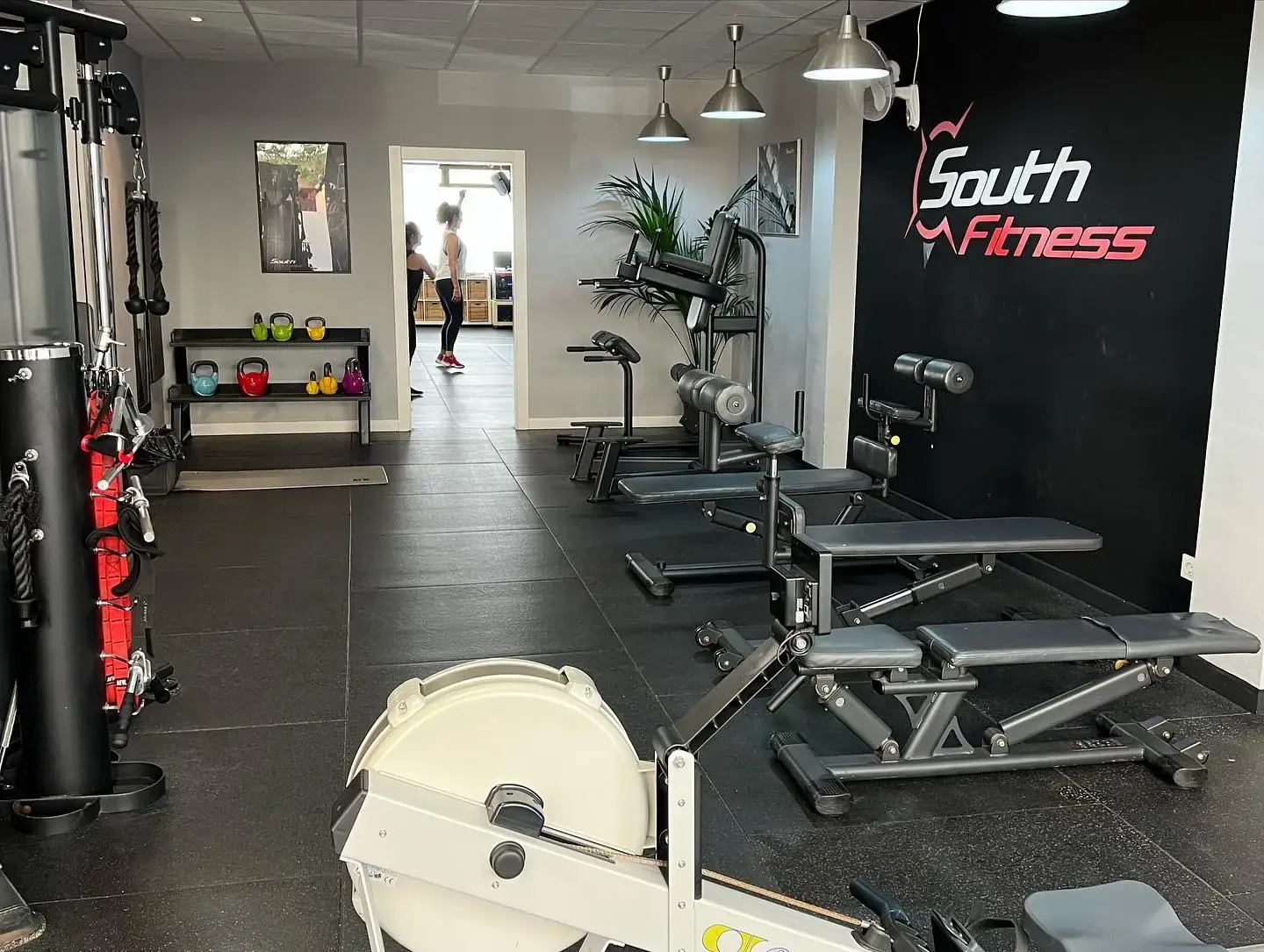 Bancos de abdominales, remo y estantería de pesas rusas bajo el logotipo de South Fitness
