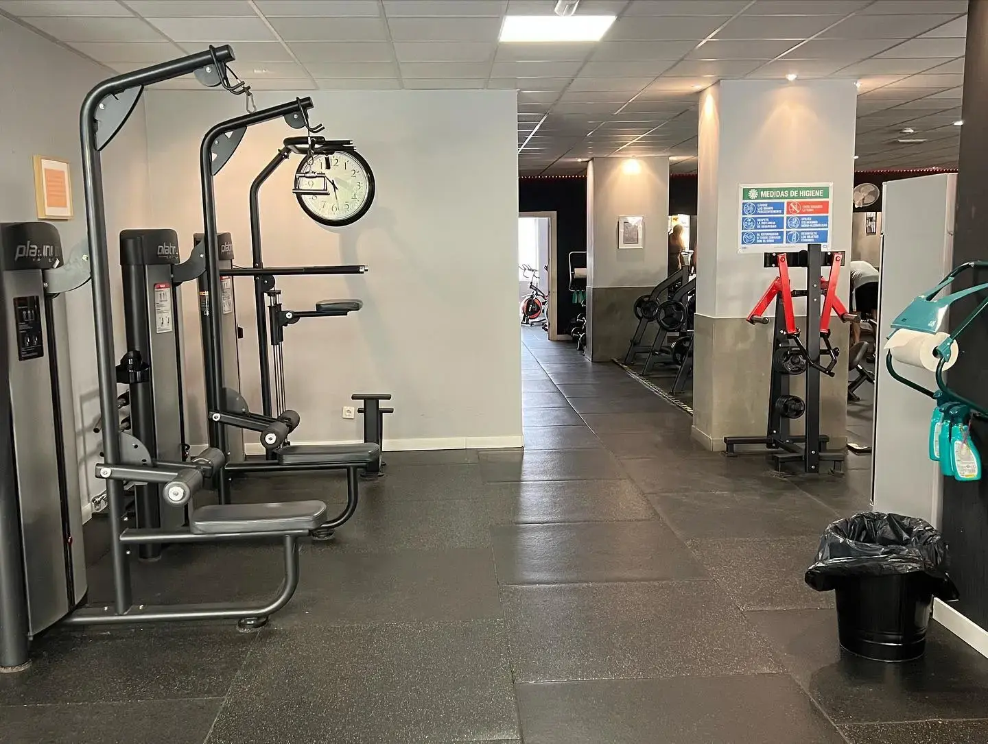Máquinas de musculación y pasillo con suelo de caucho hacia el fondo del gimnasio