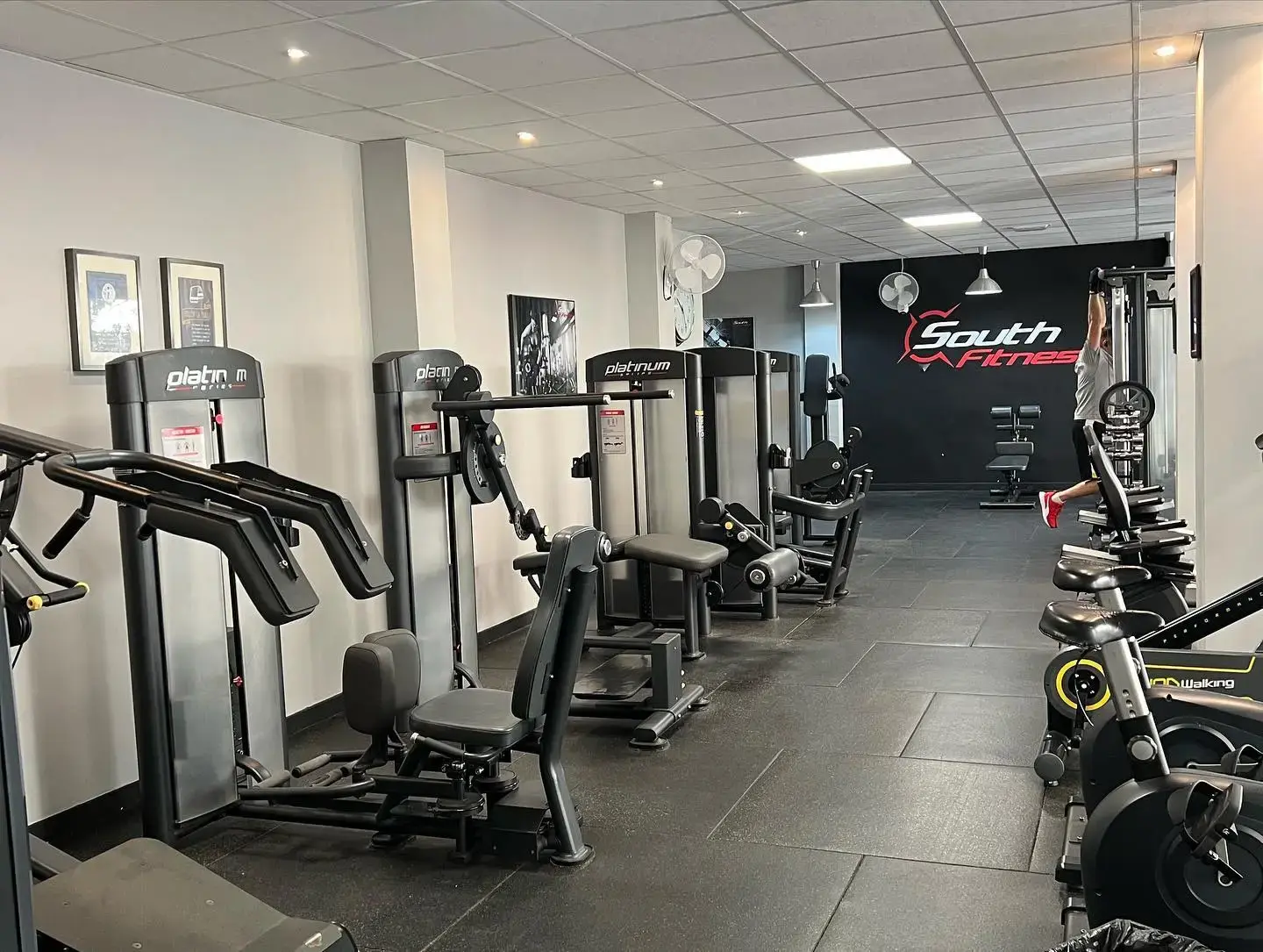 Fila de máquinas guiadas y bicicletas estáticas en la sala principal de South Fitness