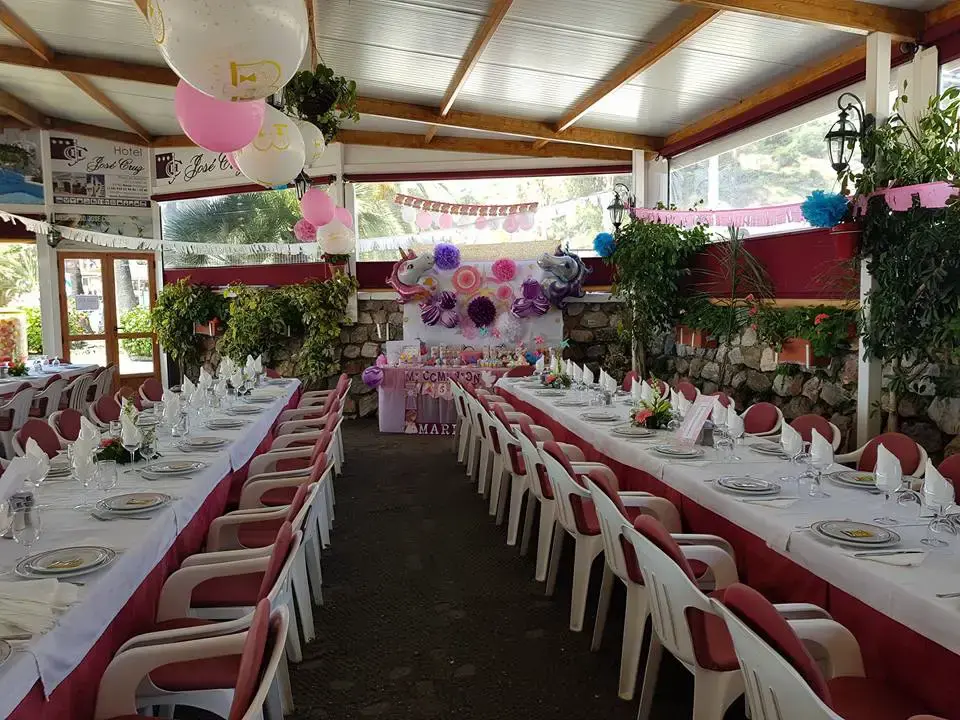 Comedor decorado en rosa y lila para una fiesta, con mesa de recuerdos al fondo