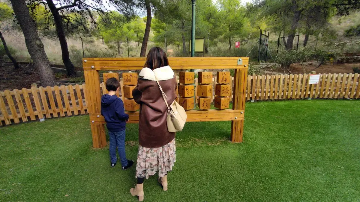 Panel de juego con cubos de madera giratorios junto a la valla del parque infantil Cueva de Nerja