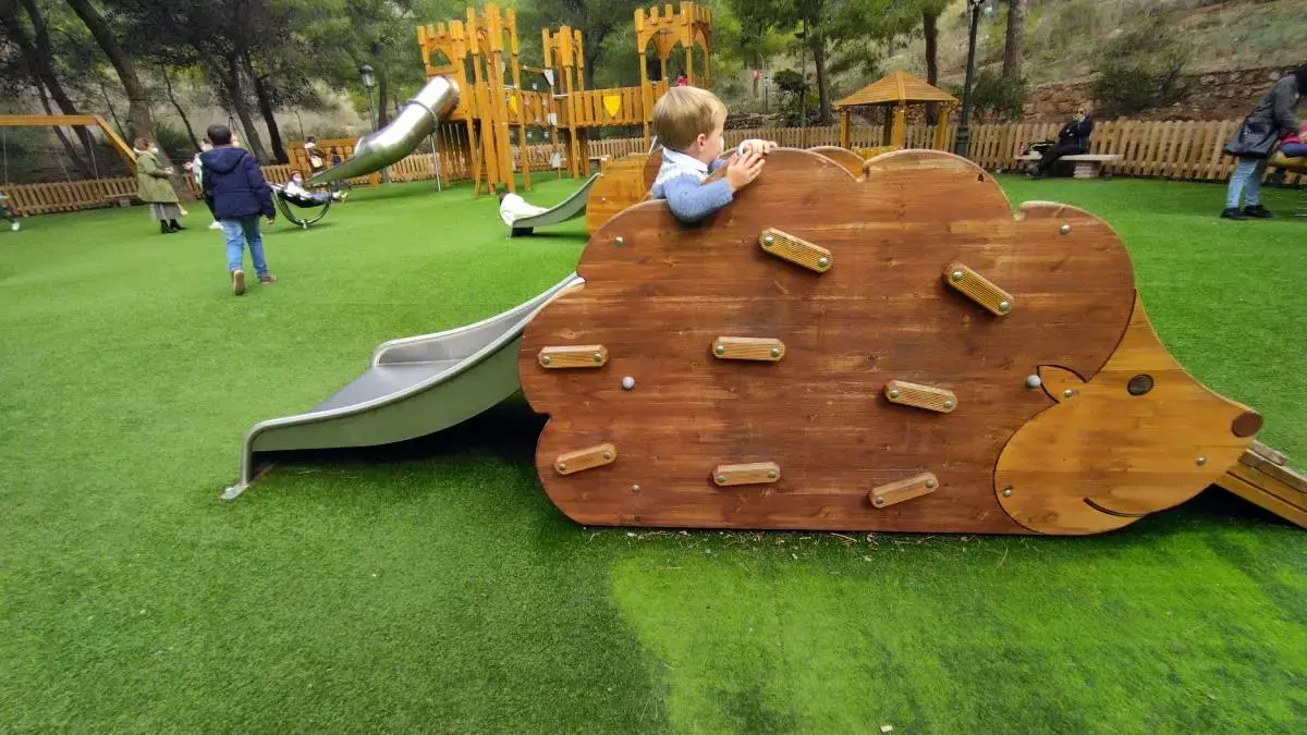 Juego de madera con forma de erizo, rocódromo y tobogán sobre césped artificial