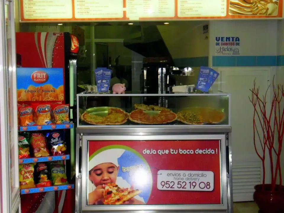 Vitrina con pizzas enteras, nevera de refrescos y estante de patatas fritas de bolsa