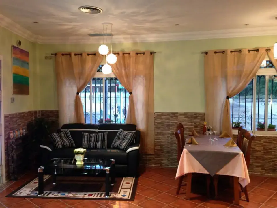 Rincón con sofá negro, mesa de cristal y una mesa puesta junto a la ventana