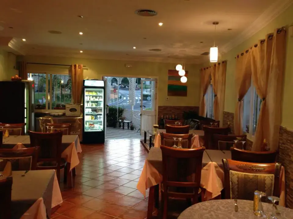 Comedor con suelo de barro, cortinas claras y la puerta de entrada al fondo