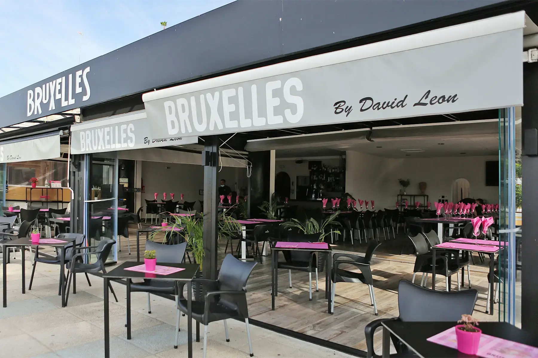 Terraza abierta con toldos «Bruxelles by David Leon» y mesas con manteles rosas