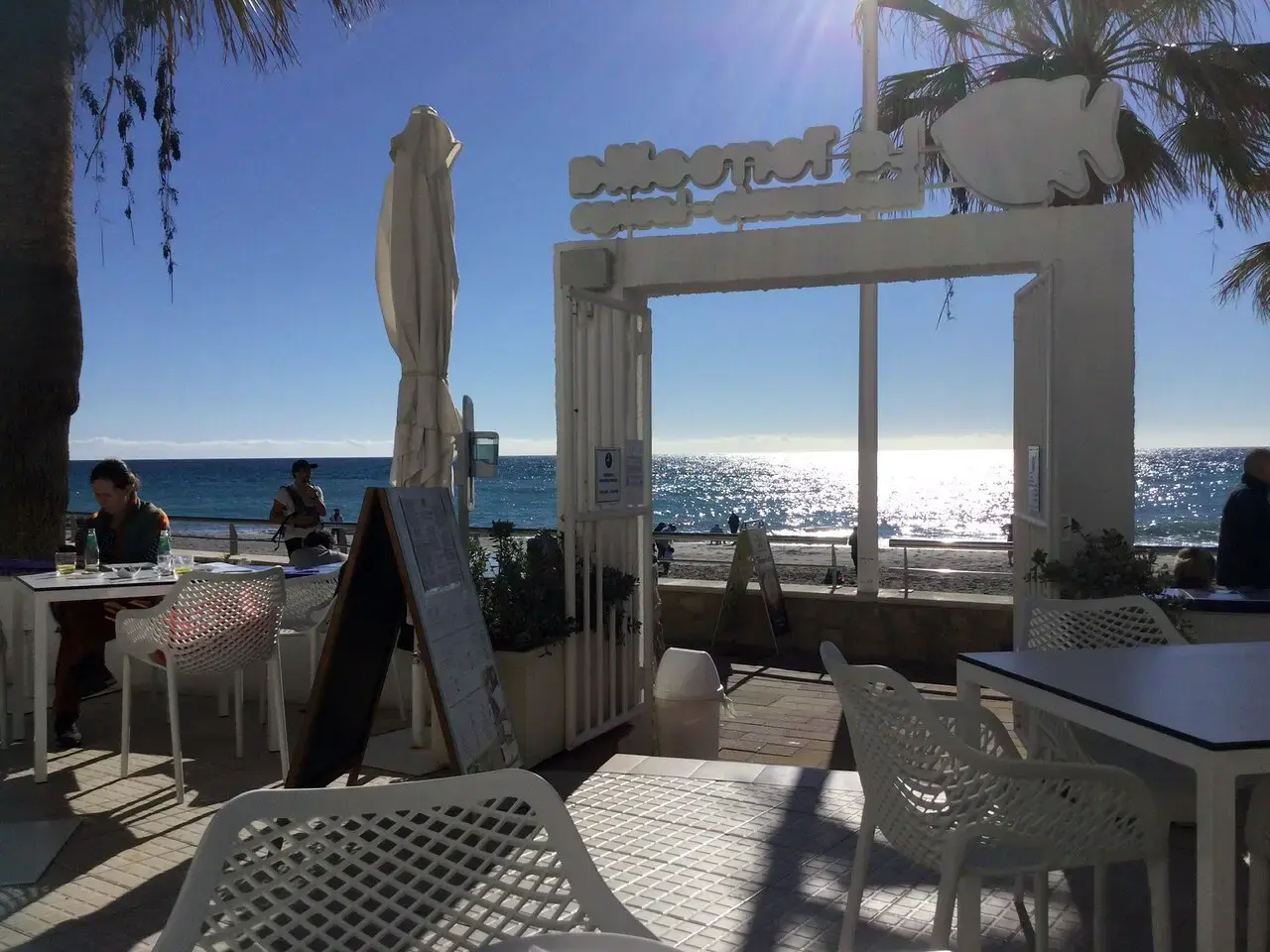 Pórtico blanco de la terraza abierto a la playa y al mar a contraluz