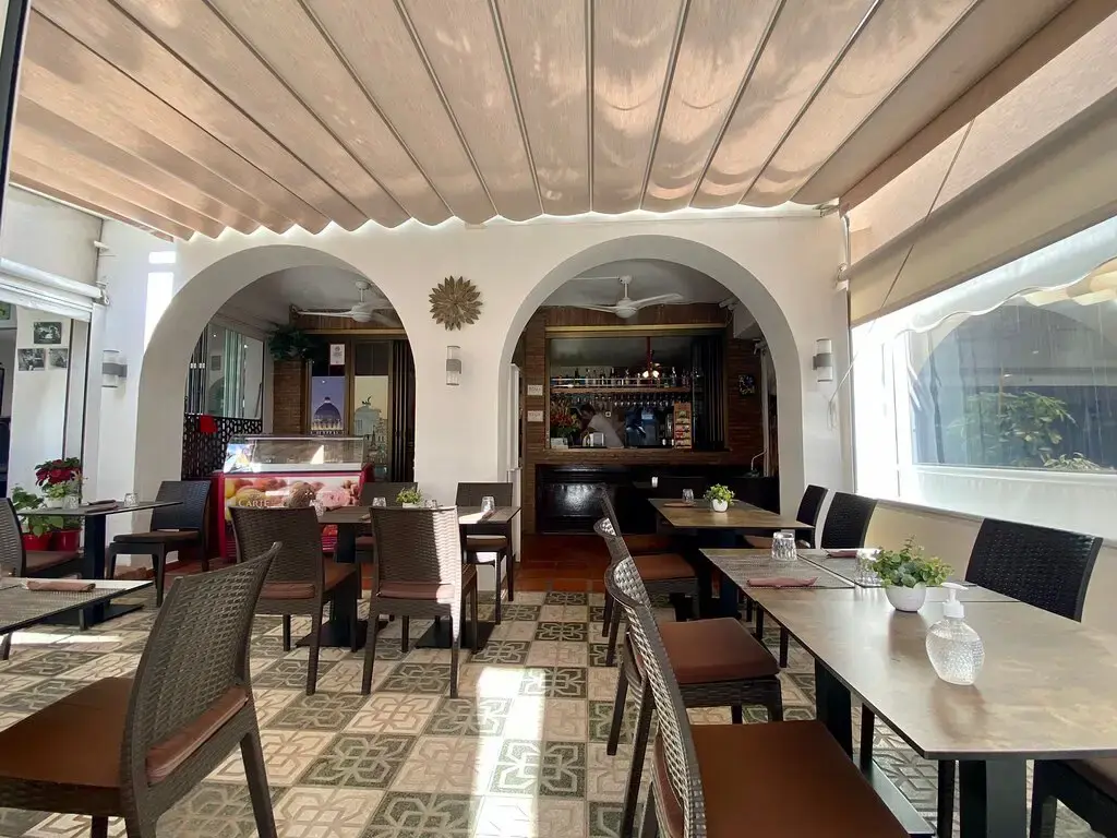 Comedor con arcos blancos, suelo hidráulico y toldo, con la barra al fondo