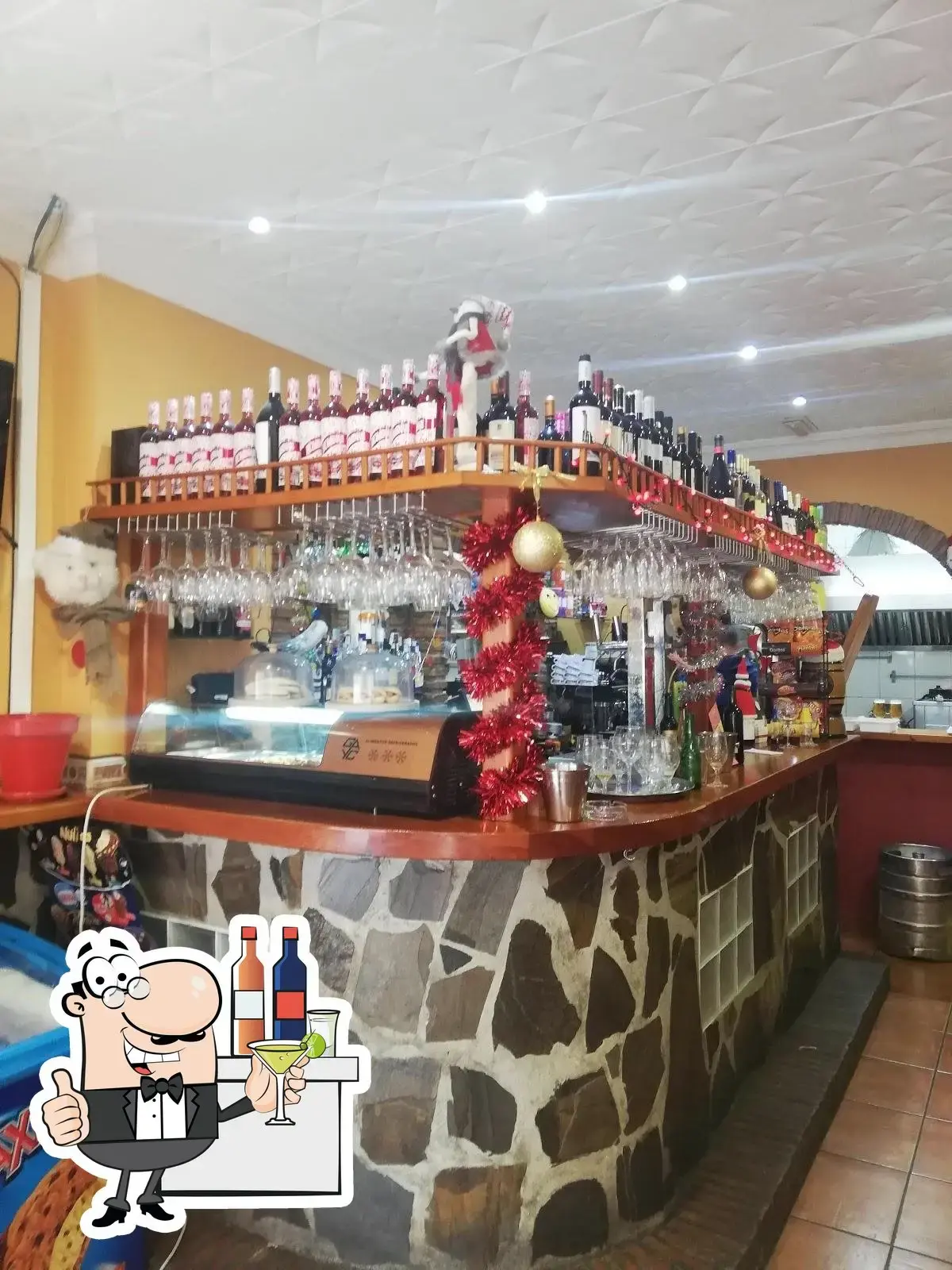 Barra de piedra con botellero, copas colgadas y adornos navideños