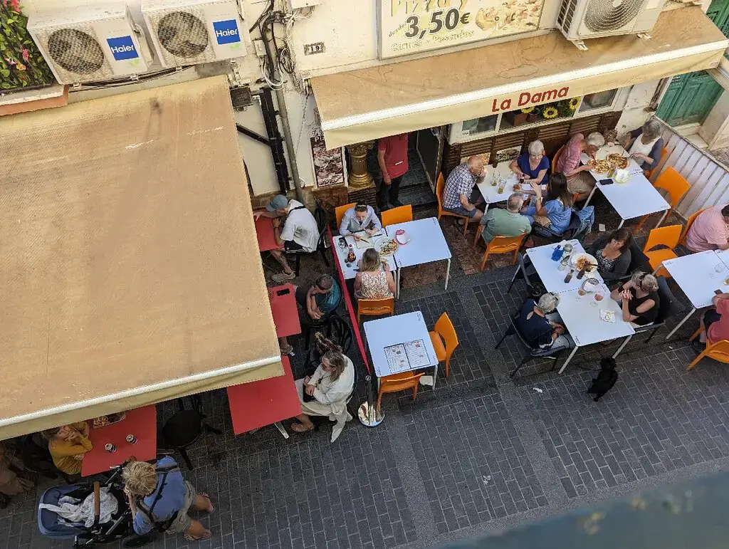 Terrazas de la calle vistas desde arriba, con mesas ocupadas bajo los toldos