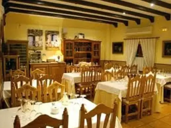 Comedor rústico con vigas de madera, sillas de enea y manteles blancos