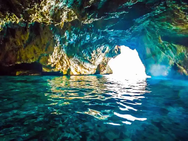 Interior de una cueva marina con agua cristalina y la salida al mar iluminada