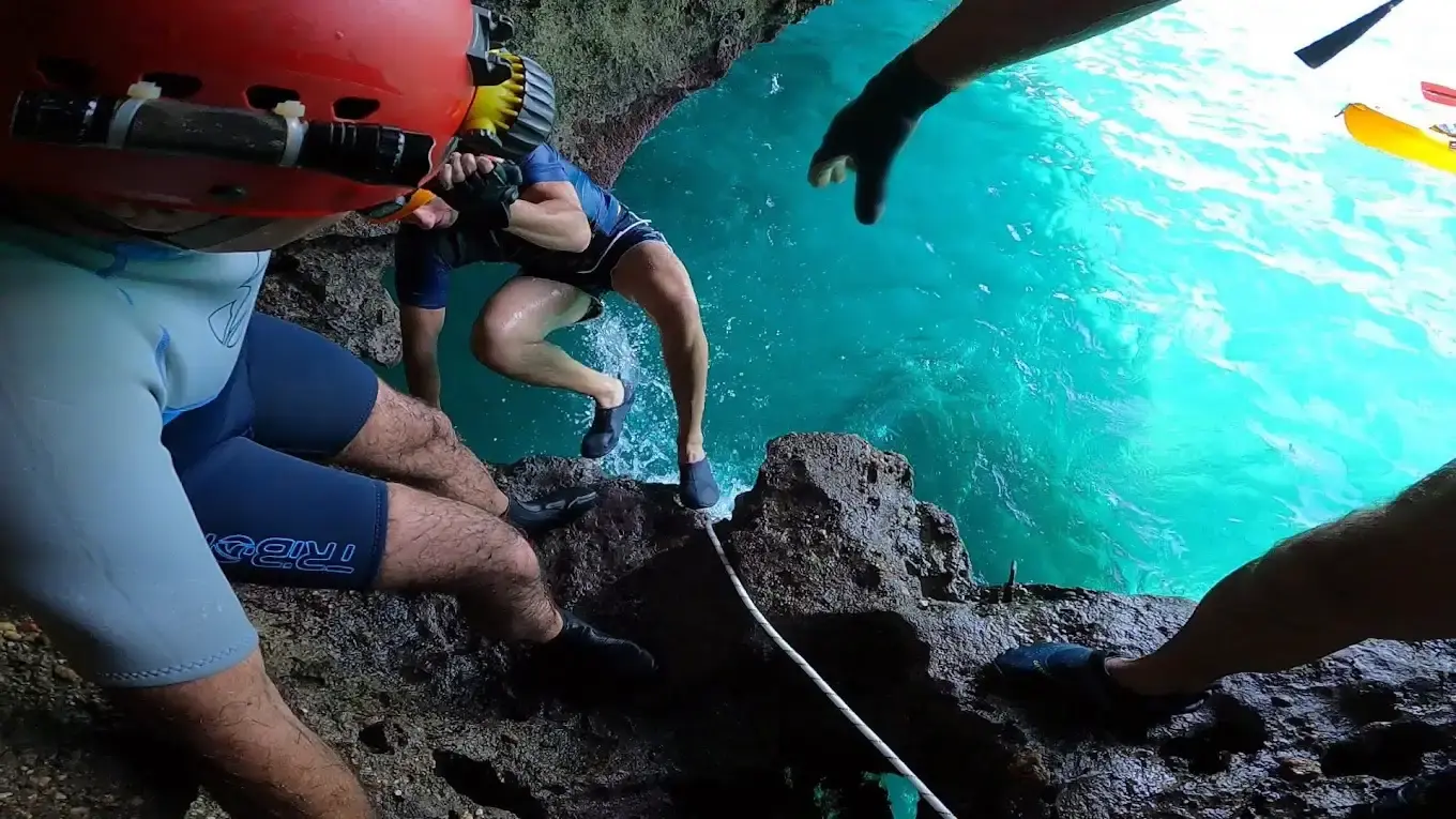 Excursionistas con casco saltando desde las rocas al mar junto a la Cueva del Lobo Marino