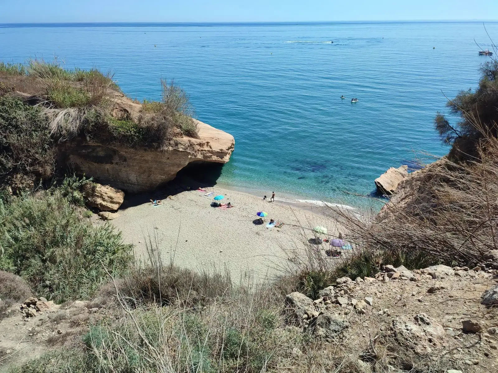 La playa Piedra de Tarzán desde la bajada, con sombrillas y bañistas en el agua