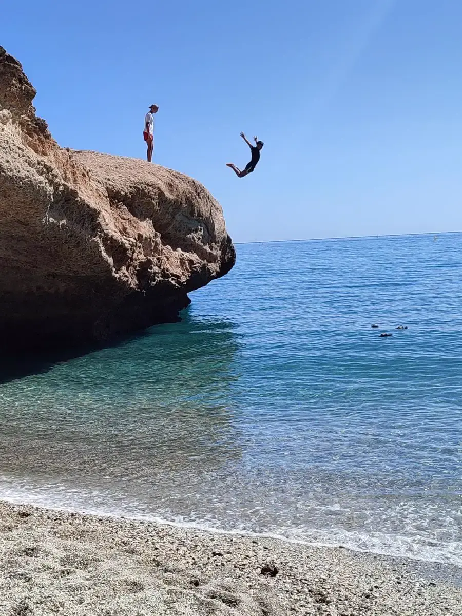 Un joven salta al agua desde la roca de la playa Piedra de Tarzán