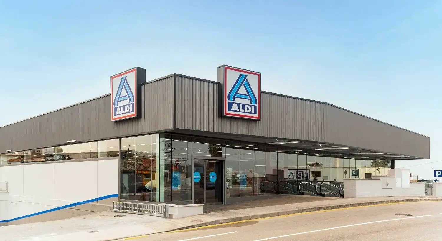 Edificio de ALDI Nerja con entrada acristalada, logotipos y rampa hacia el aparcamiento