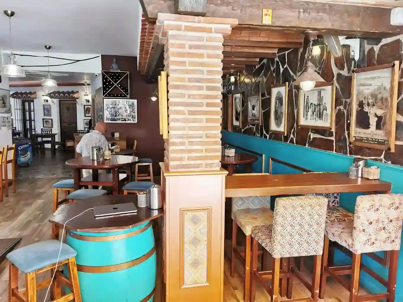 Interior con mesa de barril turquesa, columna de ladrillo y taburetes tapizados