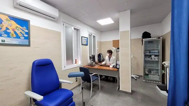 Consulta del Centro de Salud de Nerja con sillón de extracciones azul, mesa y frigorífico de medicamentos
