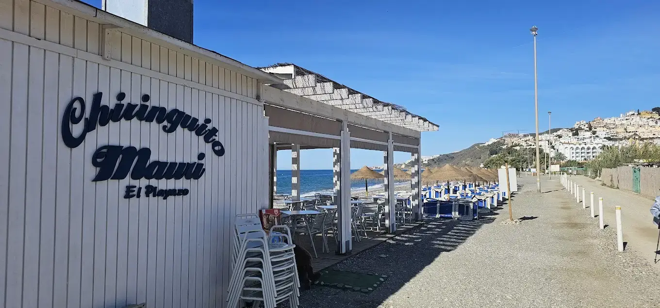 Rótulo del Chiringuito Mauri en El Playazo, con la terraza junto al mar y Nerja al fondo