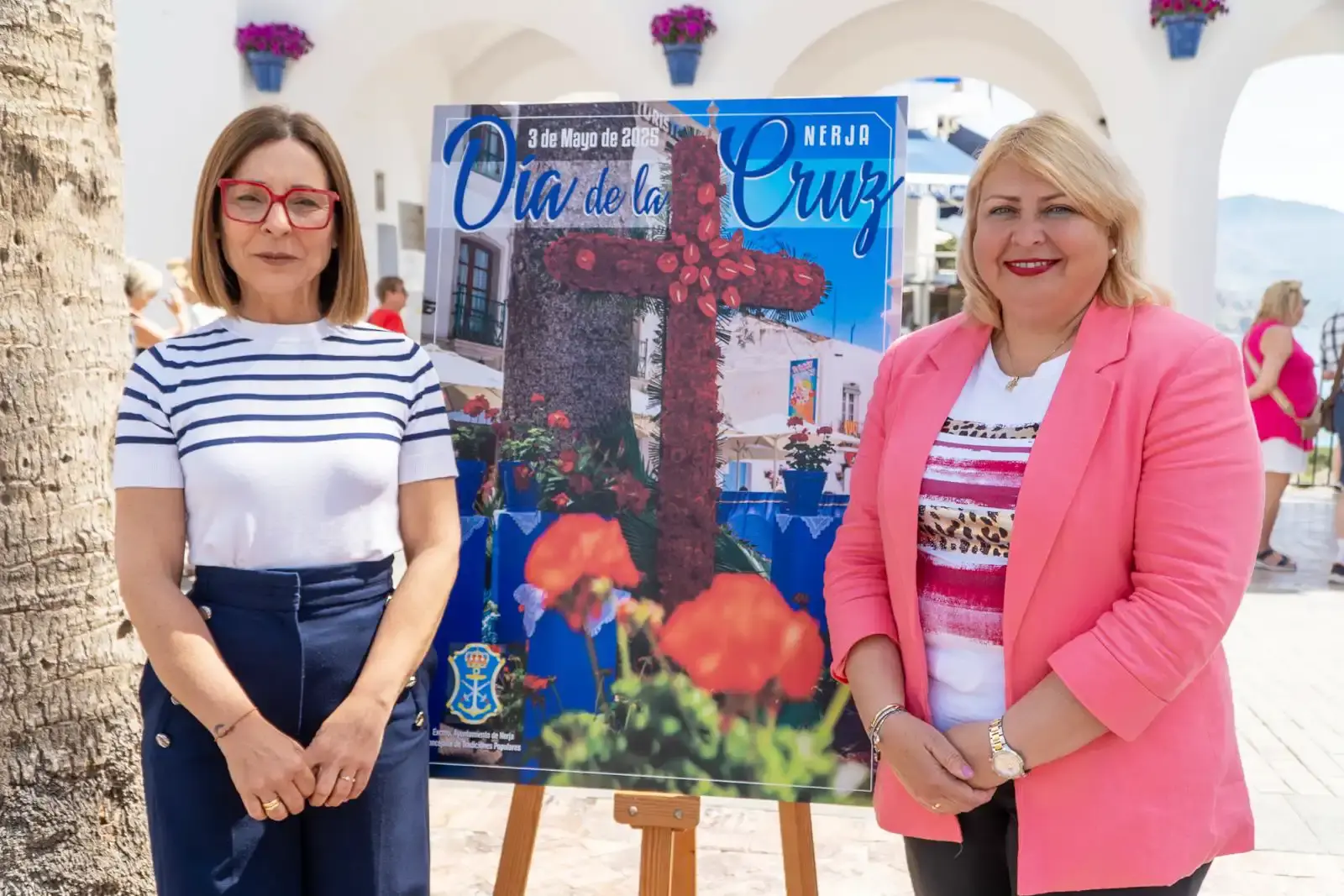 Presentación del cartel del Día de la Cruz de Nerja, con dos mujeres junto al atril