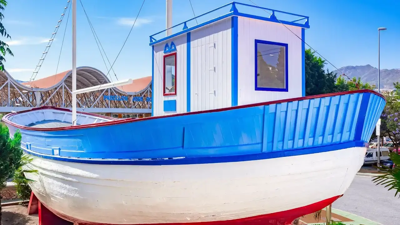 Cubierta y cabina blanca y azul del barco, con una cubierta de madera al fondo