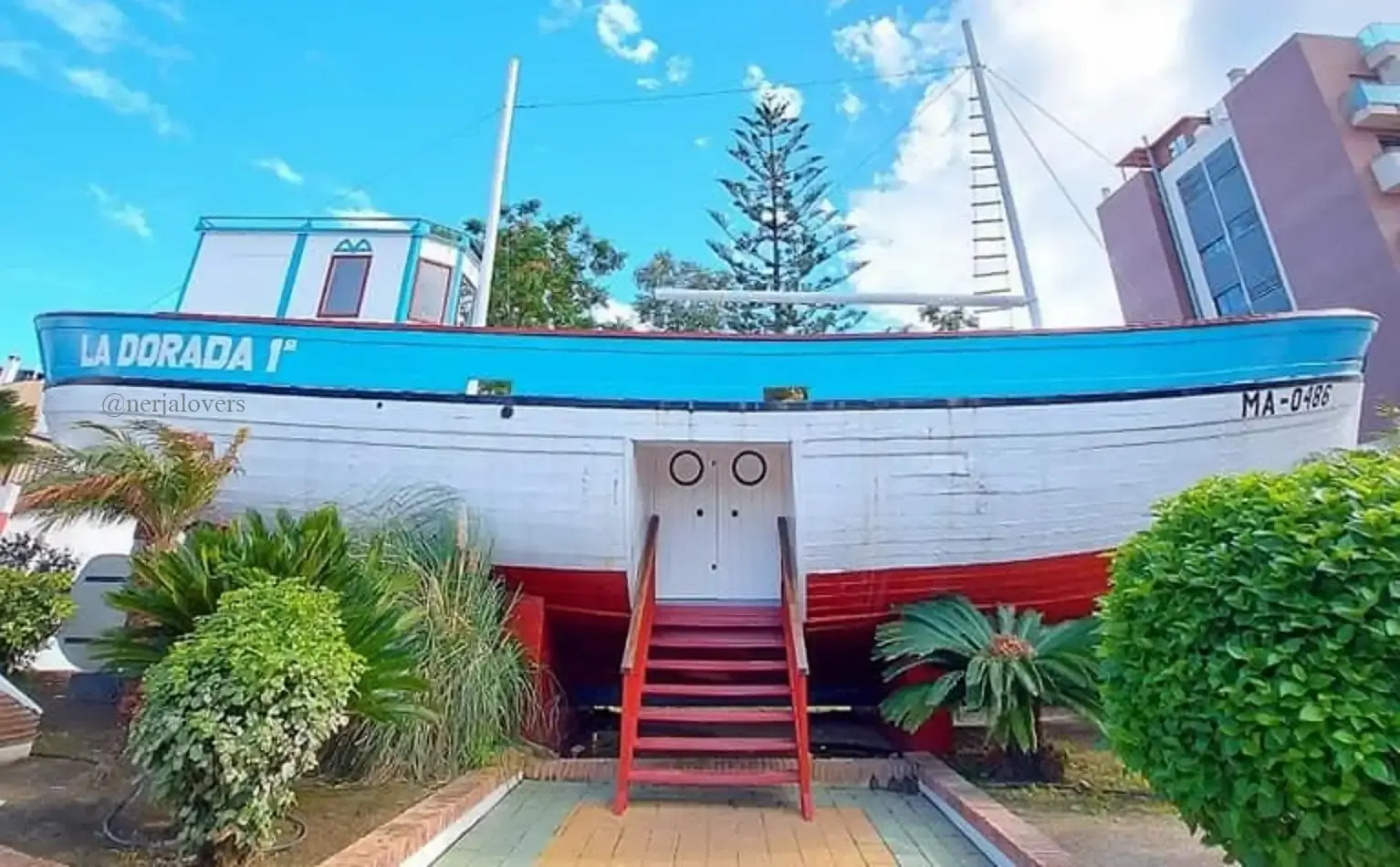 Popa de La Dorada con la puerta y la escalera roja de acceso, rodeada de plantas