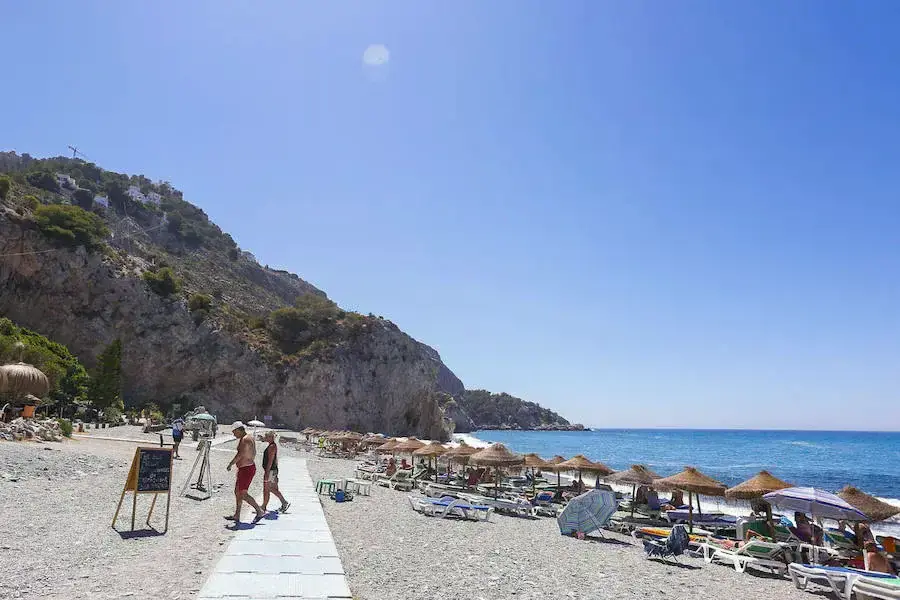 Pasarela de madera y hamacas con sombrillas de paja en la playa de Cantarriján