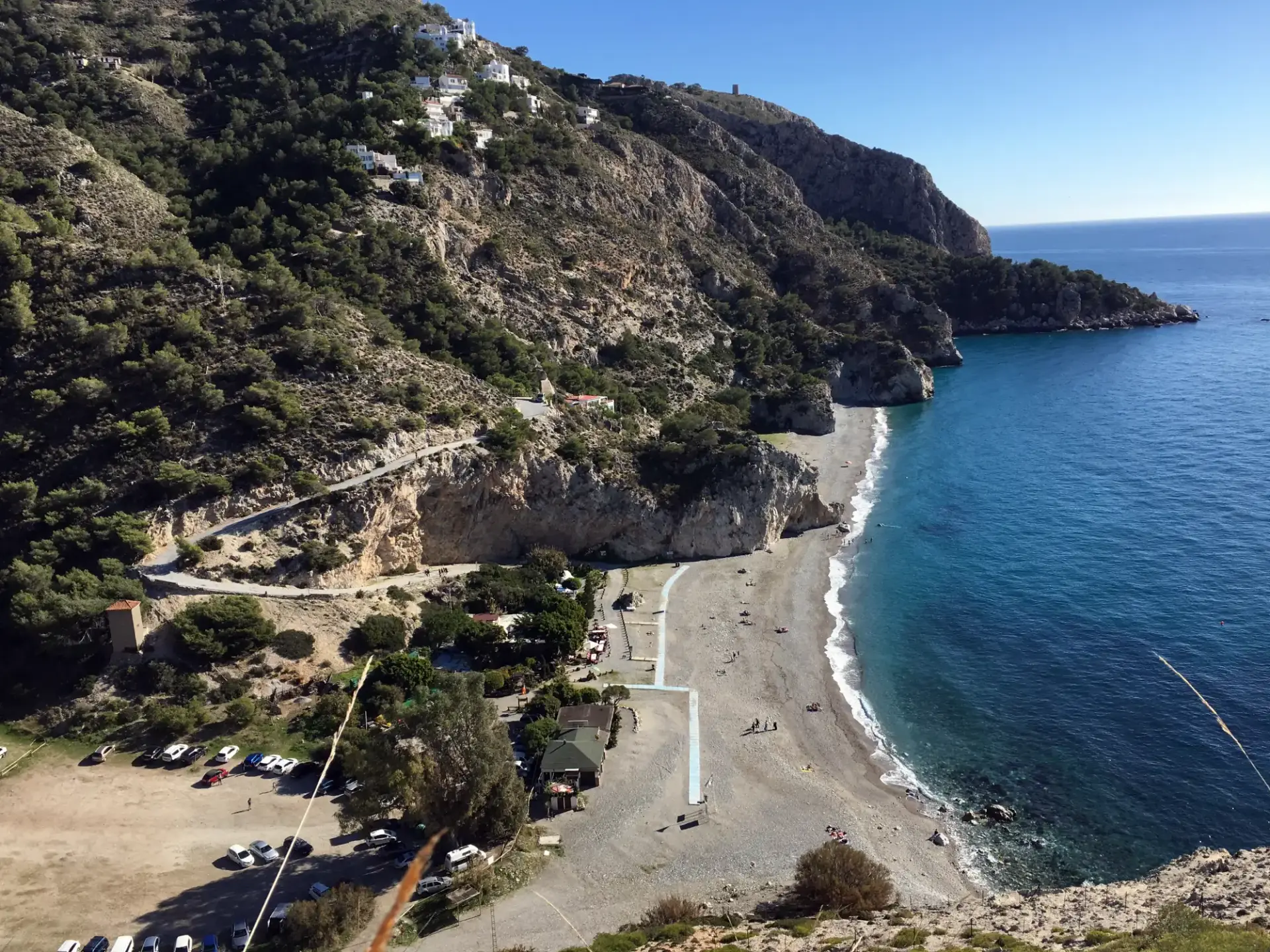 La playa de Cantarriján desde el camino de bajada, con el aparcamiento y los acantilados