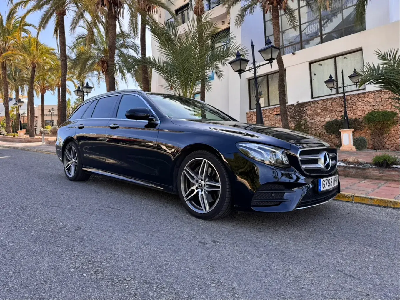 Mercedes familiar negro del servicio de transfer aparcado junto a palmeras