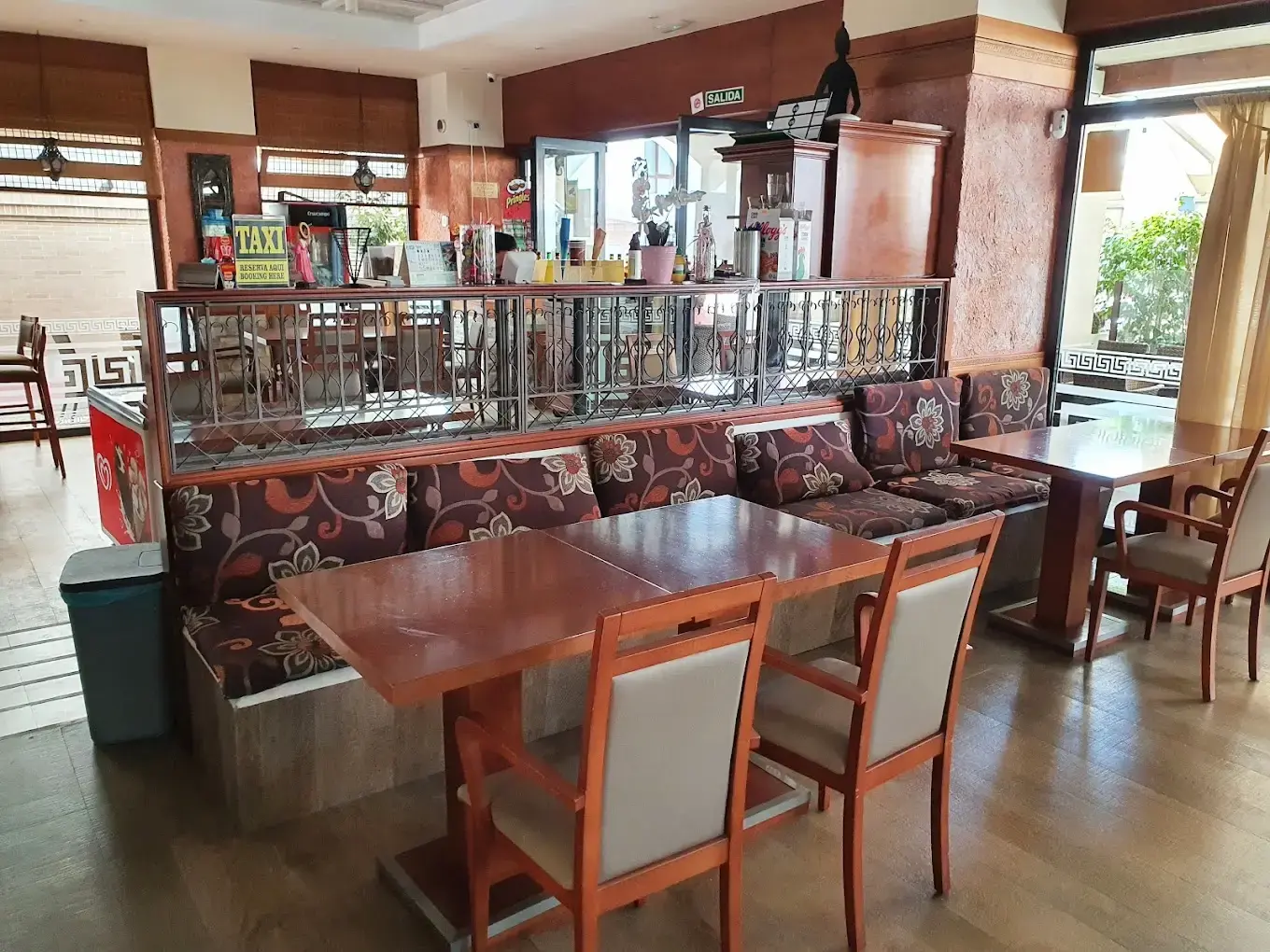 Interior con bancos tapizados de flores, mesas de madera y barra al fondo