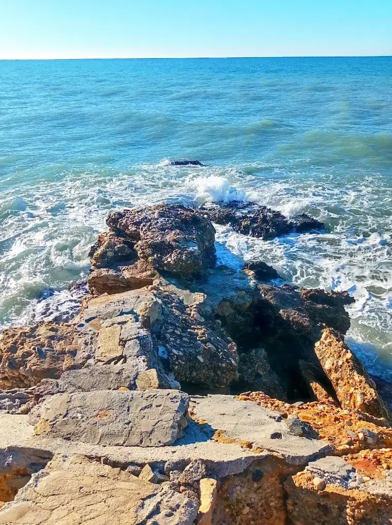 Rocas de la punta del mirador entrando en el mar, con espuma de las olas