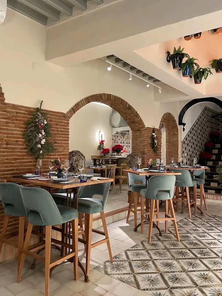 Zona de mesas altas con taburetes verdes, suelo hidráulico y adornos navideños en Casa Luque