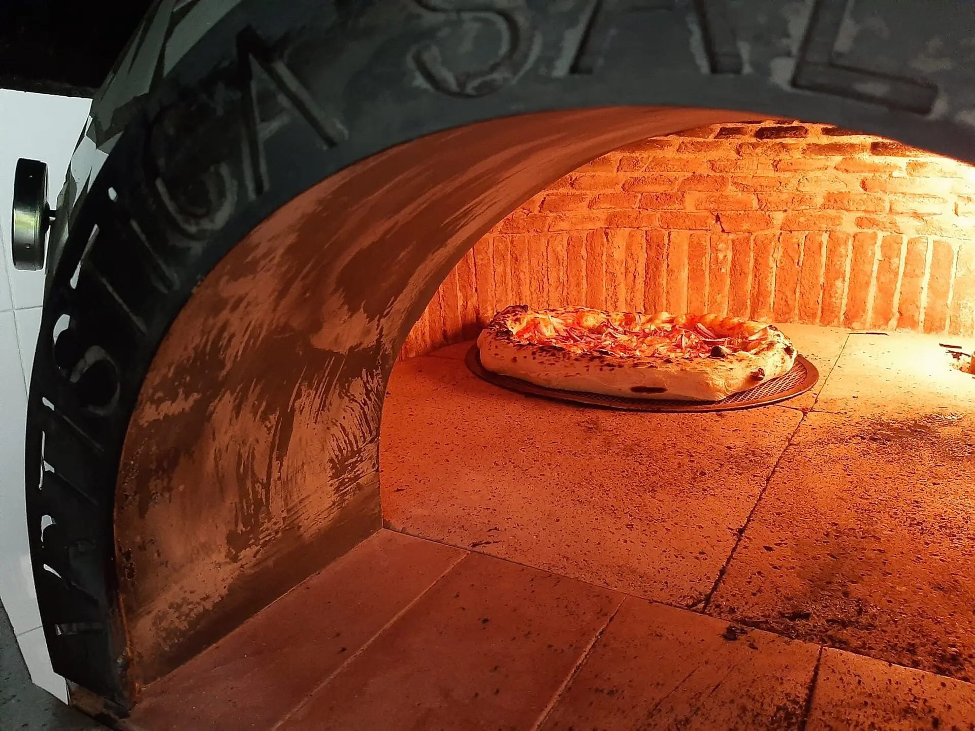 Pizza cociéndose dentro del horno de ladrillo encendido