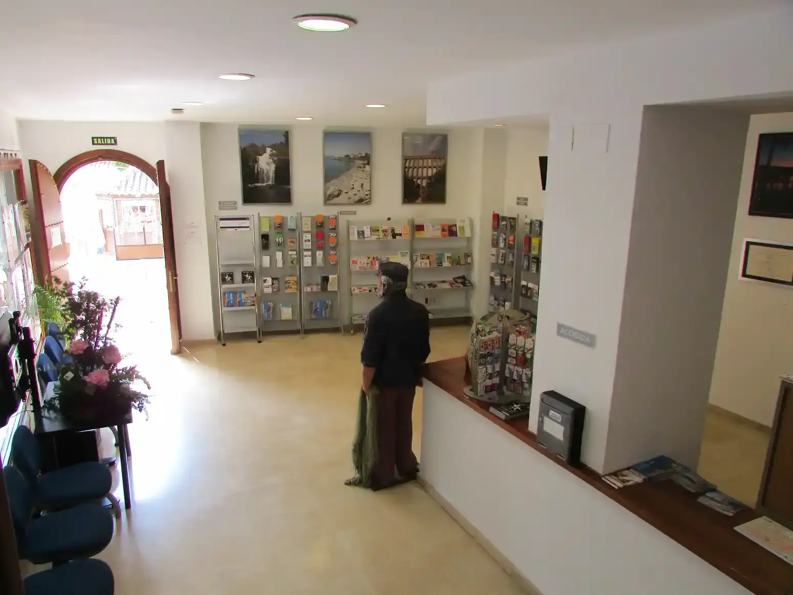 Interior de la oficina con expositores de folletos, mostrador de atención y un visitante