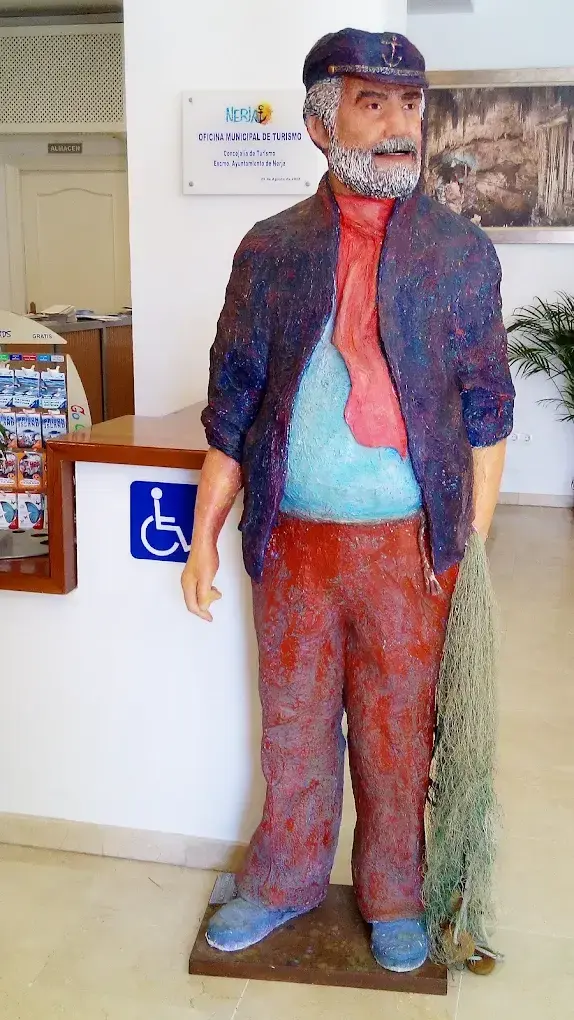 Figura de un viejo pescador con gorra y red de pesca en la entrada de la oficina