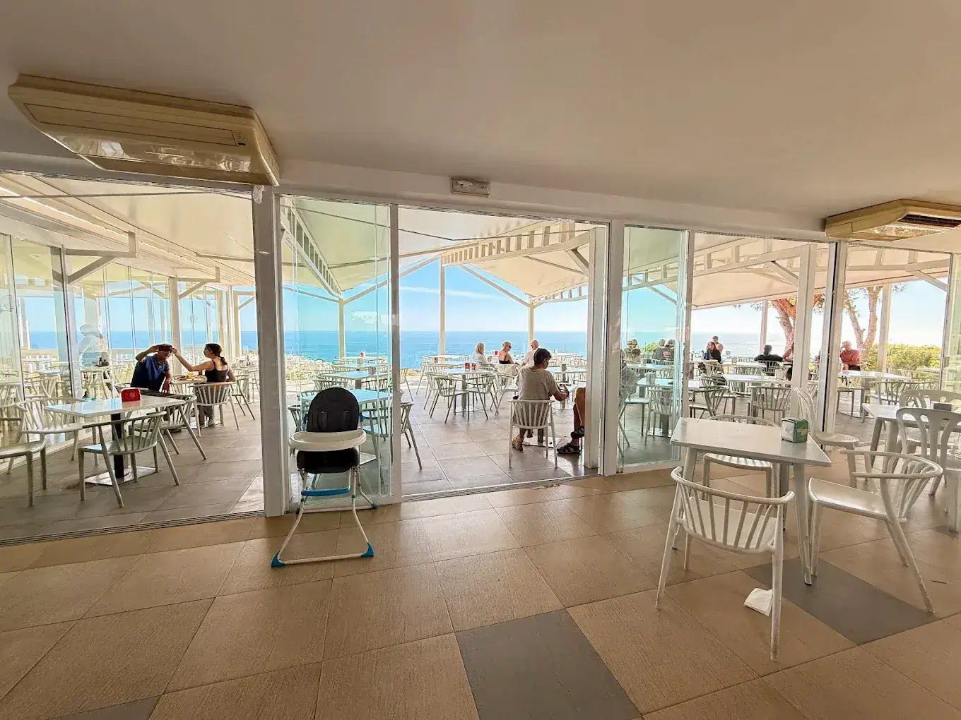 Comedor interior con ventanales abiertos a la terraza y al mar