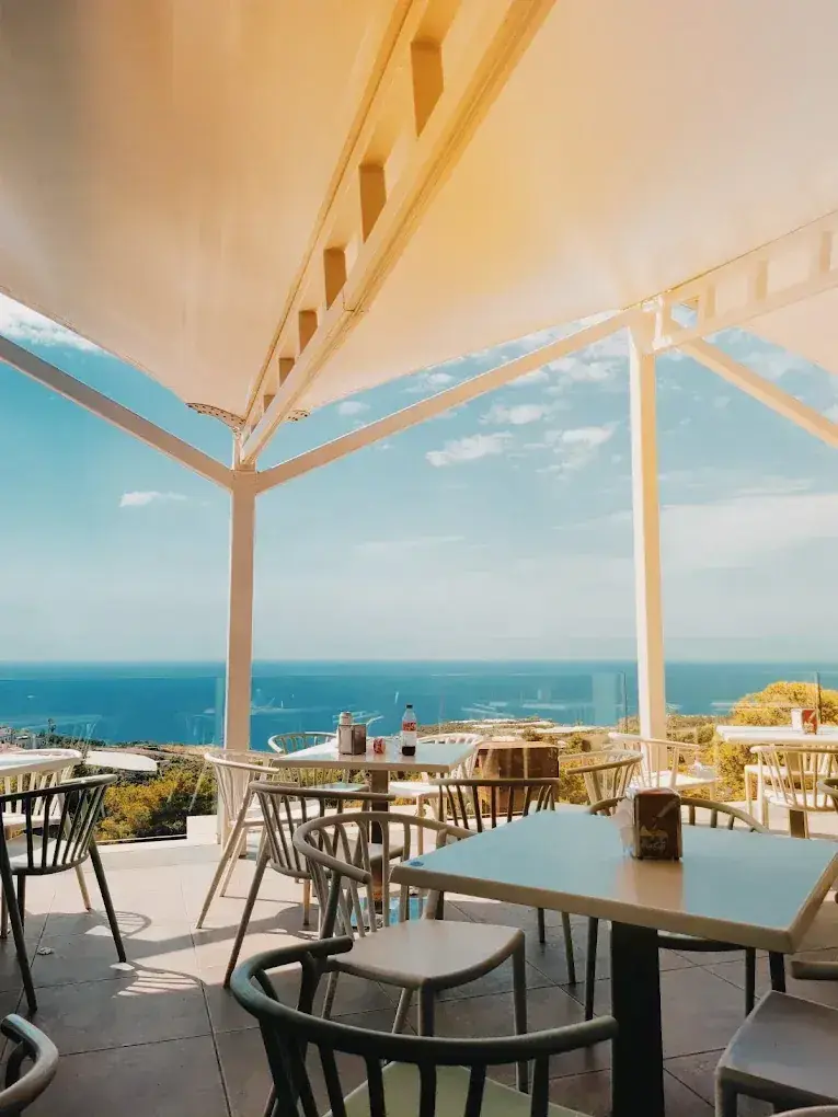 Mesas de la terraza bajo un toldo blanco con vistas al Mediterráneo