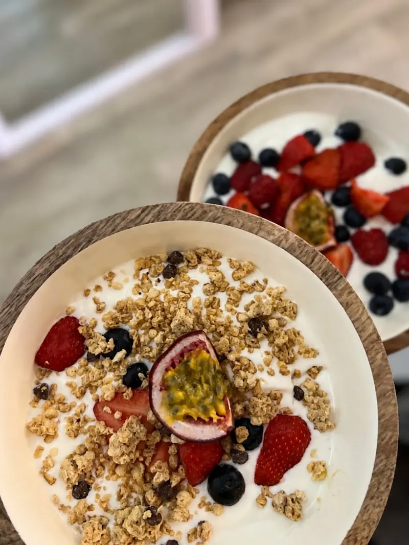 Dos boles de yogur con granola, fresas, arándanos y maracuyá