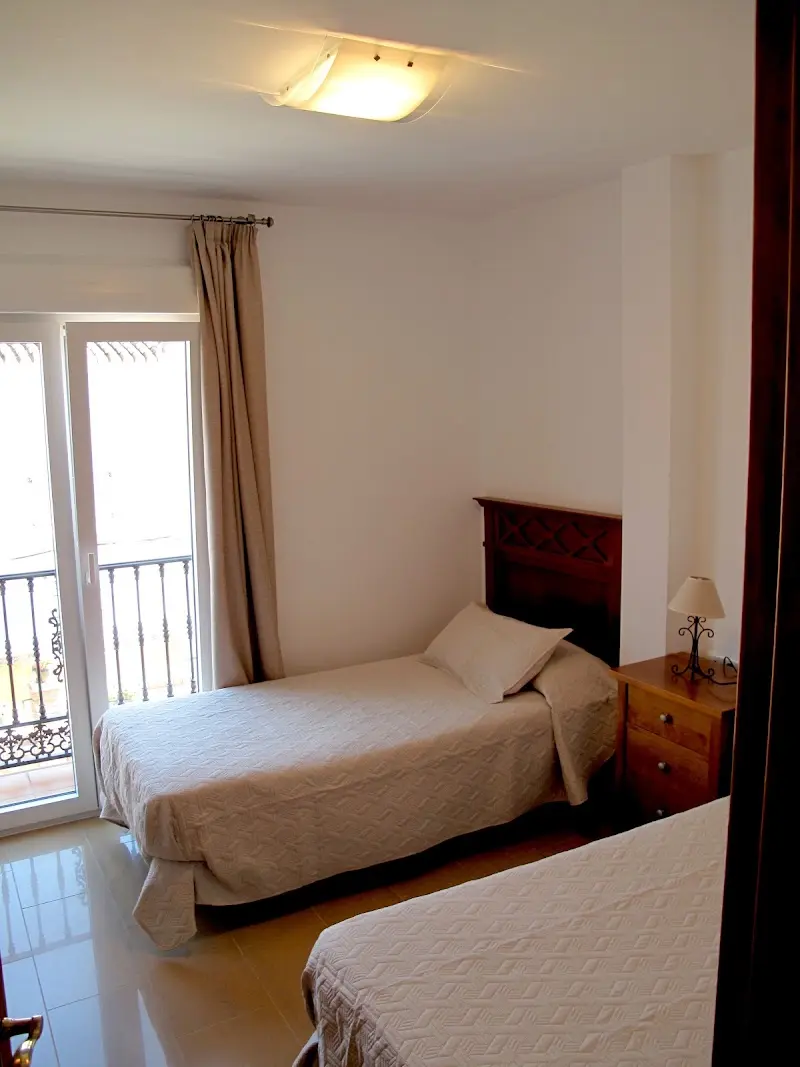Dormitorio con dos camas individuales y puerta a un balcón de forja