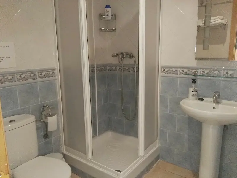 Baño con plato de ducha y mampara, lavabo de pie y azulejos azules
