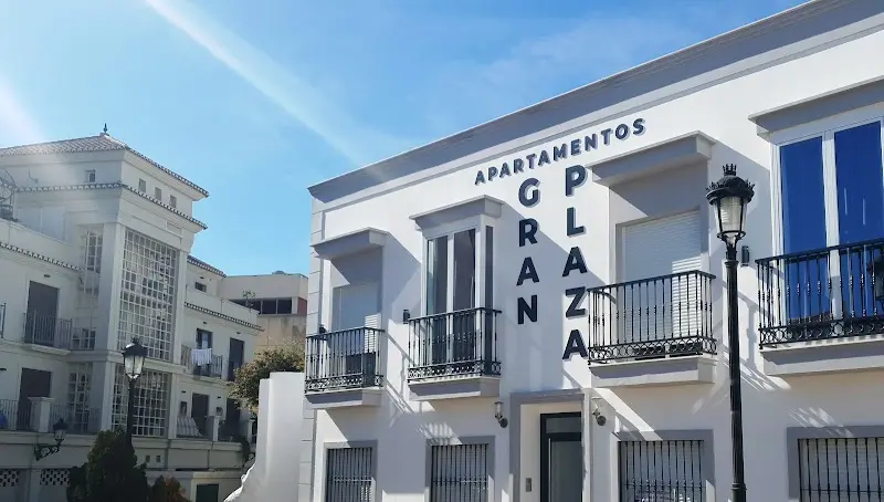 Fachada blanca de Apartamentos Gran Plaza con el rótulo en letras negras y balcones de forja