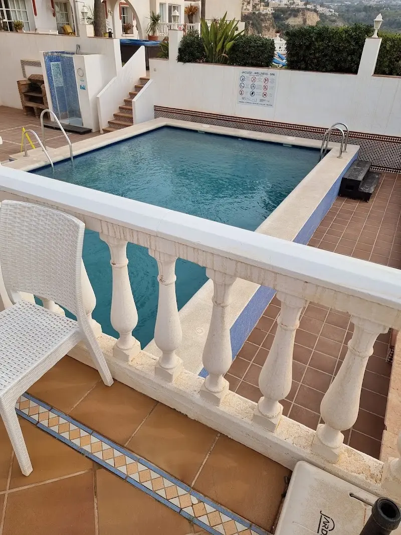 Piscina comunitaria con escaleras y suelo de barro, vista desde una terraza con balaustrada