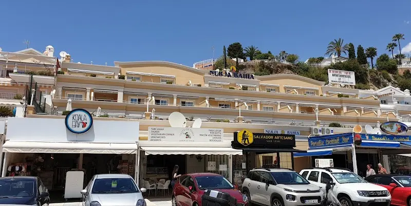 Edificio de tonos ocres con tiendas en la planta baja frente al paseo de Burriana