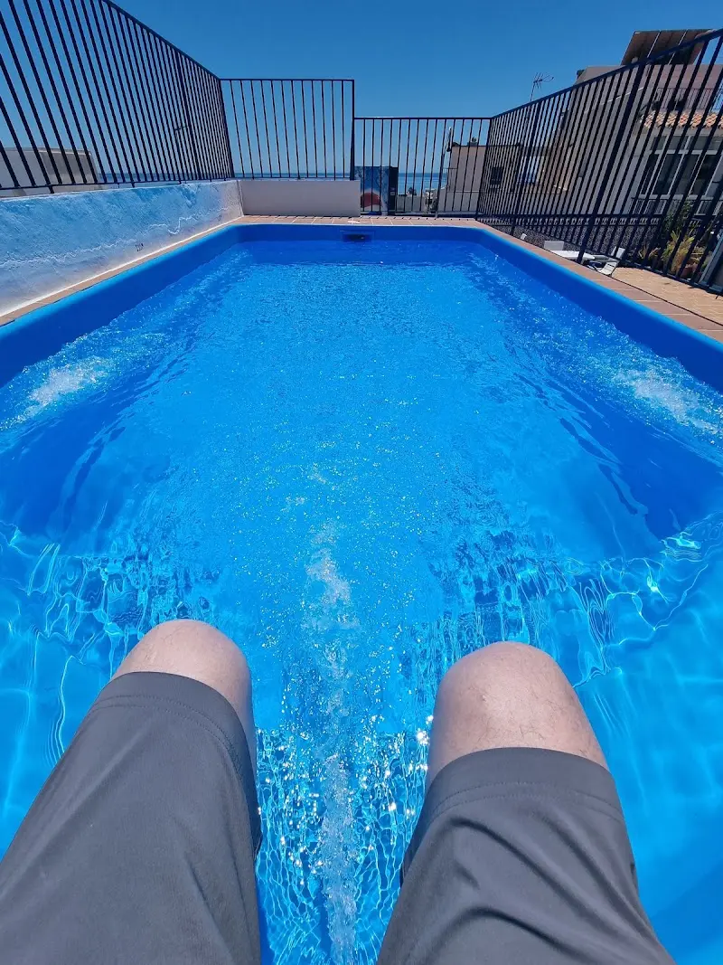 Piernas de un huésped dentro de la piscina de la azotea, con chorros de hidromasaje