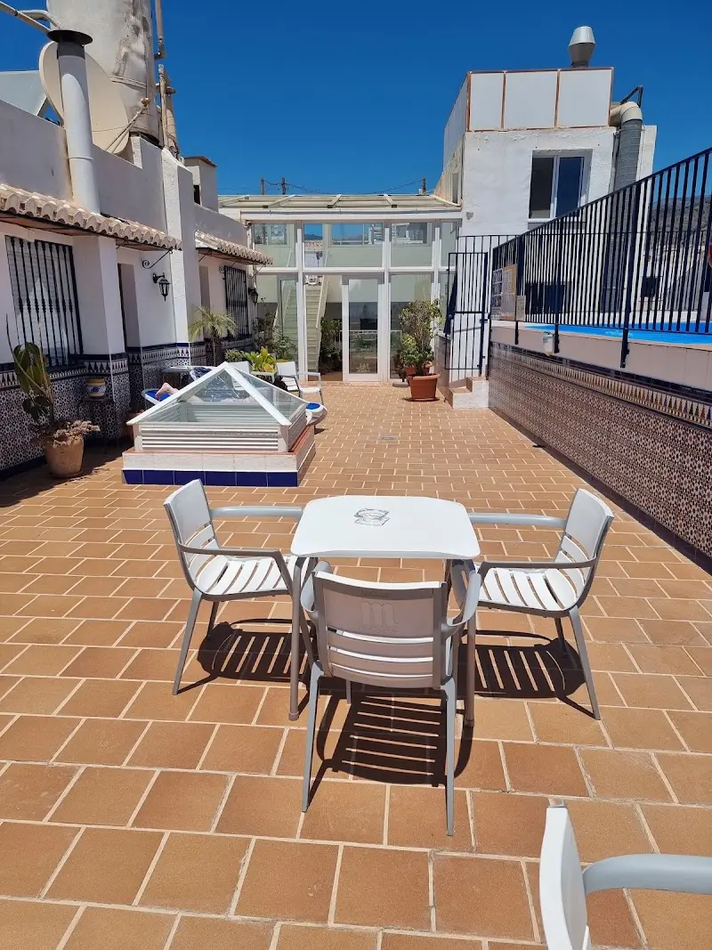 Terraza de baldosas con mesa y sillas blancas en la azotea de Apartamentos Pepe Mesa