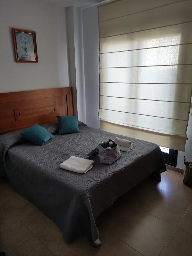 Dormitorio de los Apartamentos Plaza del Olvido con cama de matrimonio, cojines turquesa y toallas