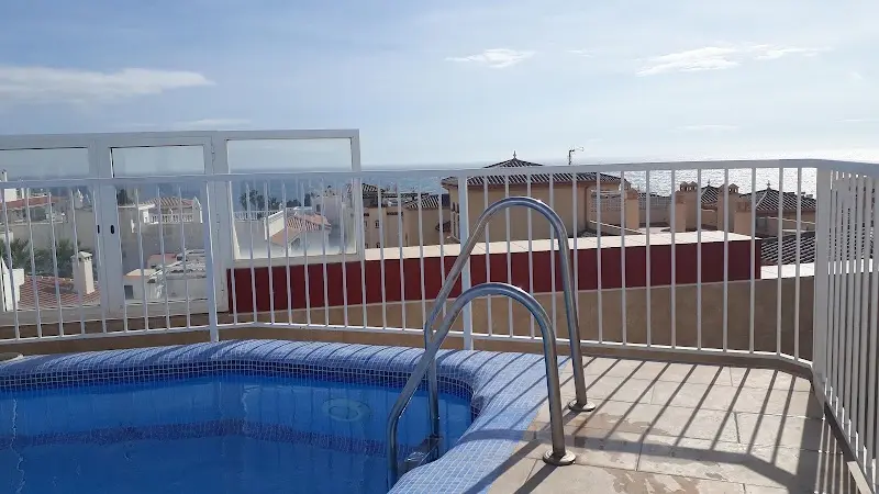 Escalerilla de la piscina de la azotea con tejados de Nerja y el mar al fondo