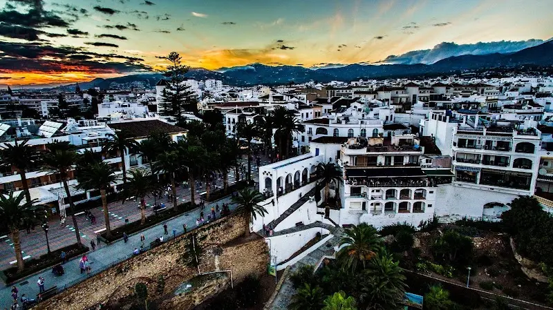 Vista aérea del centro de Nerja al atardecer, con un paseo de palmeras y la sierra al fondo