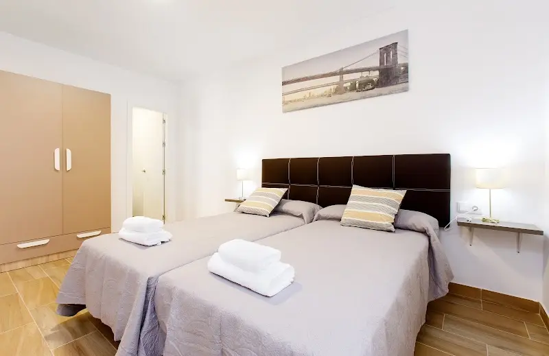 Habitación de Armijorooms con dos camas individuales juntas, cabecero marrón y armario