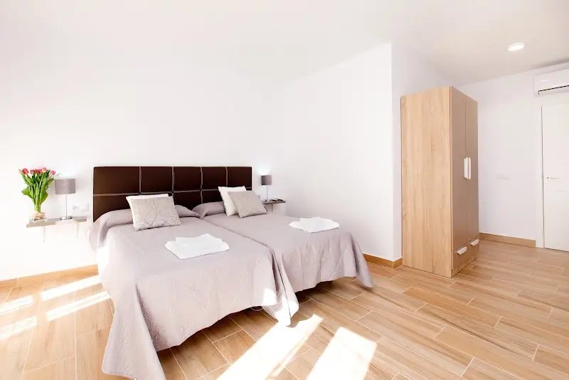 Habitación amplia con dos camas, suelo de madera, armario y ramo de tulipanes